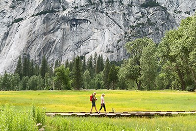 Two people walking along a boardwalk in Yosemite Valley.