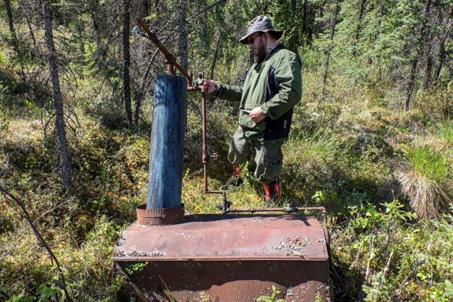 NPS historian Chris Allan examines the "doghouse boiler" at Colorado Creek in Yukon-Charley Rivers National Preserve, June 2015.