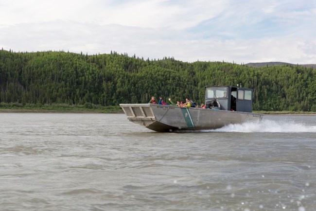 A large motorboat carries a crew of workers on the Yukon River