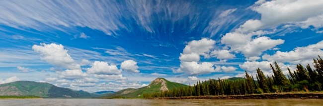 A panoramic photo of clouds above a bluff on the Yukon River