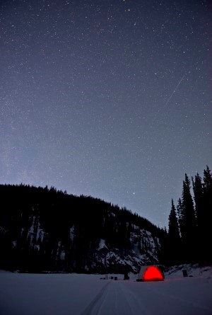 The star-filled night sky above a winter campsite on the Charley River
