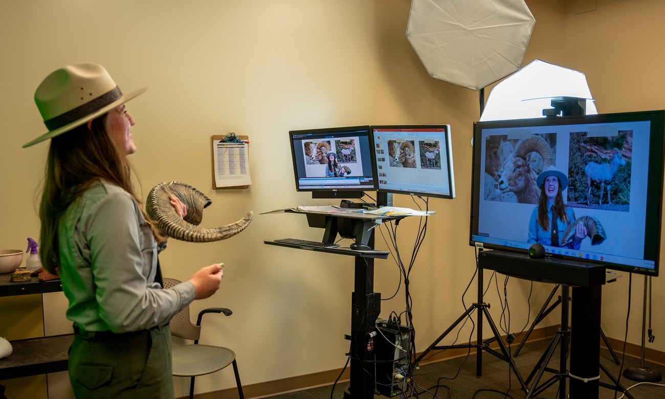 A park ranger holds up a bighorn sheep skull and presents to a virtual audience.