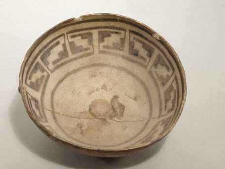 A clay bowl with a native design painted on the inside, black-on-gray.