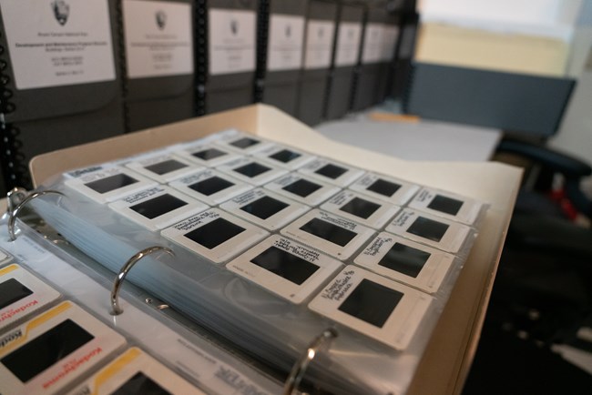 Image slides in a three ring binder with archival boxes behind them