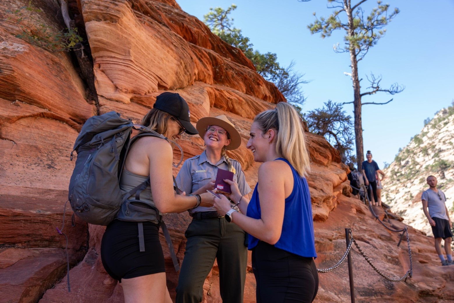 Two visitors show permits to a smiling ranger at Scout Lookout.