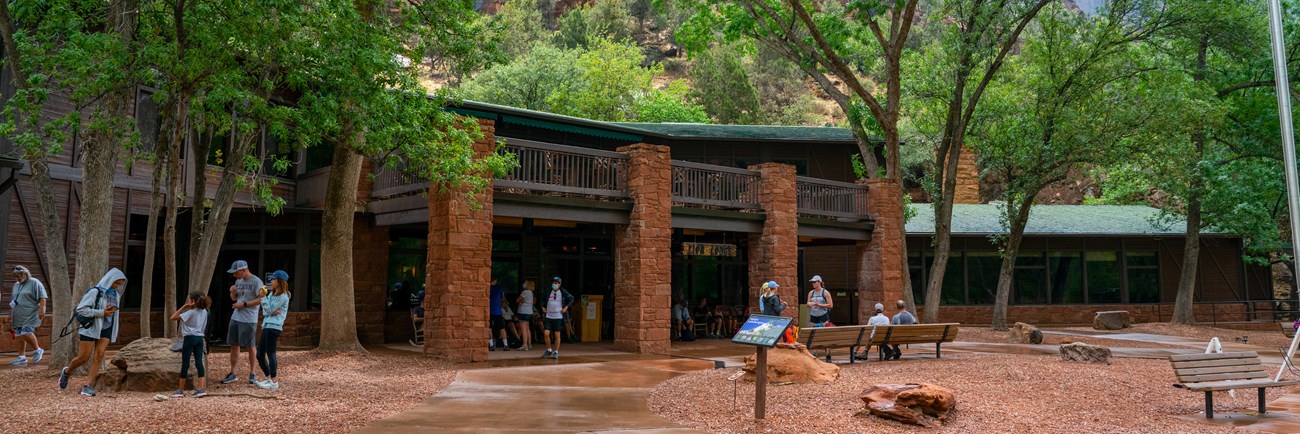 A stone lodge building with green cottonwood trees nearby.