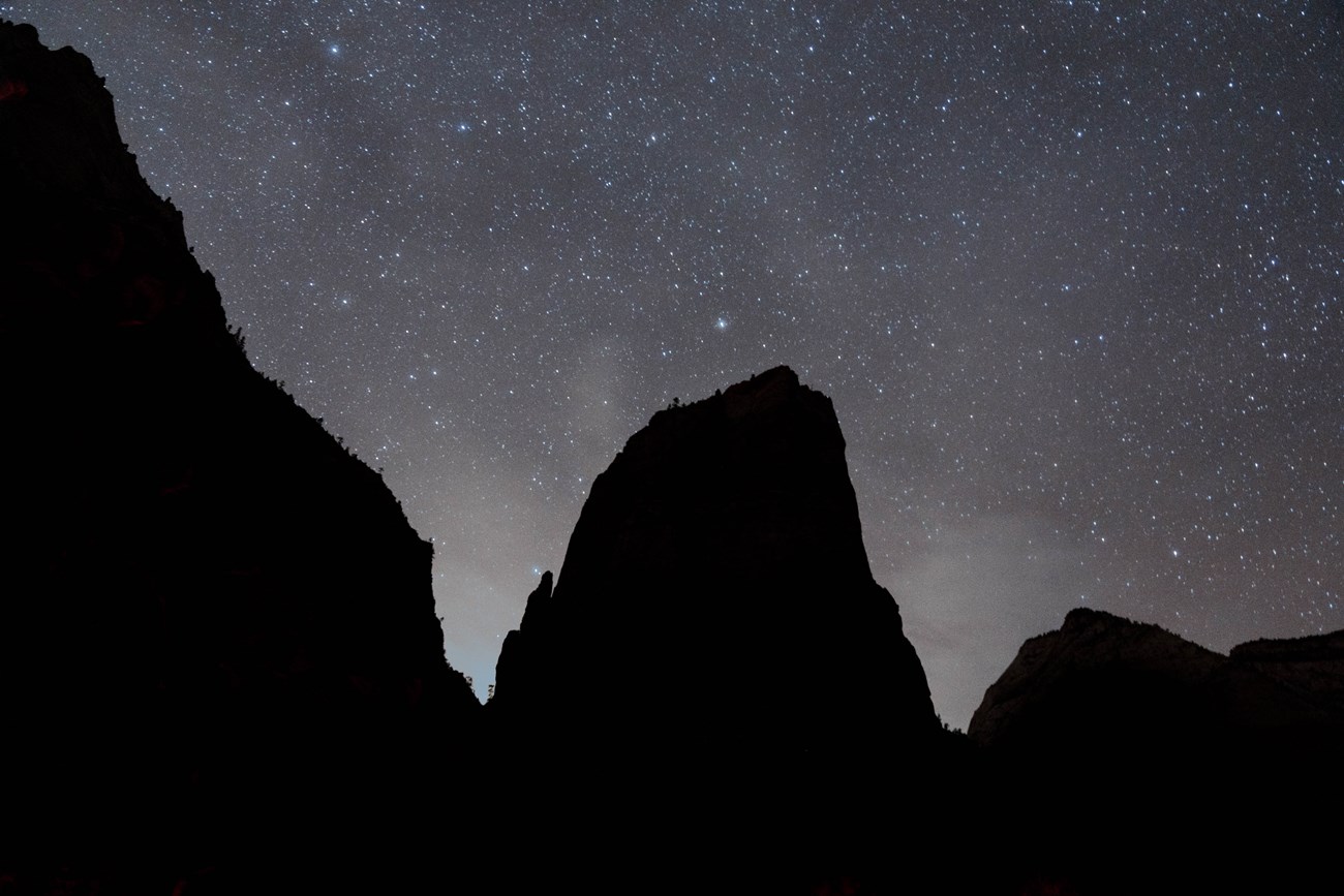 Jagged cliffs silhouetted by a starry night sky